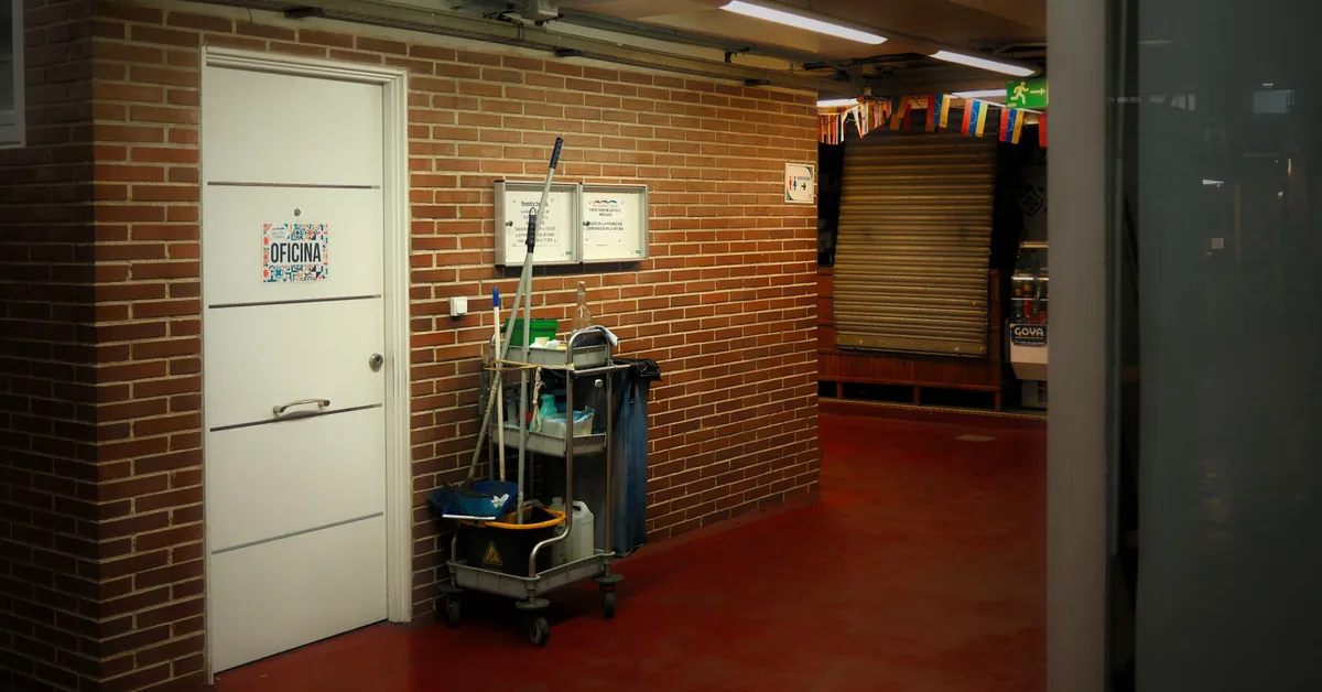 A brightly lit industrial hallway with a cleaning cart and supplies near an office door. industrial hallway with cleaning cart setup