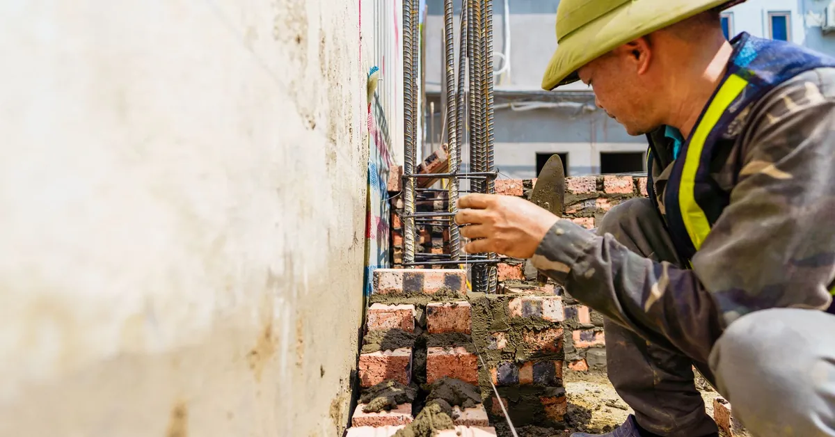 Construction worker aligning bricks on site in Hải Phòng, Vietnam, illustrating craftsmanship and dedication. construction worker building wall in h i phong