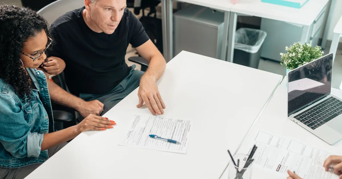 A couple discusses legal documents with a professional in a modern office setting. man couple love woman