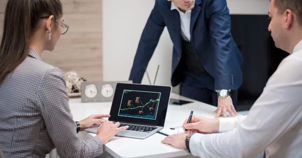 Professional team analyzing stock market trends on a laptop during a meeting. people having a meeting