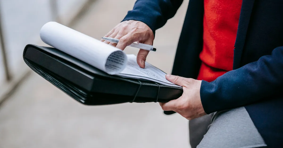 Close-up of a professional person reviewing documents outdoors. Engaged in work with focus on writing materials. person working outside blur