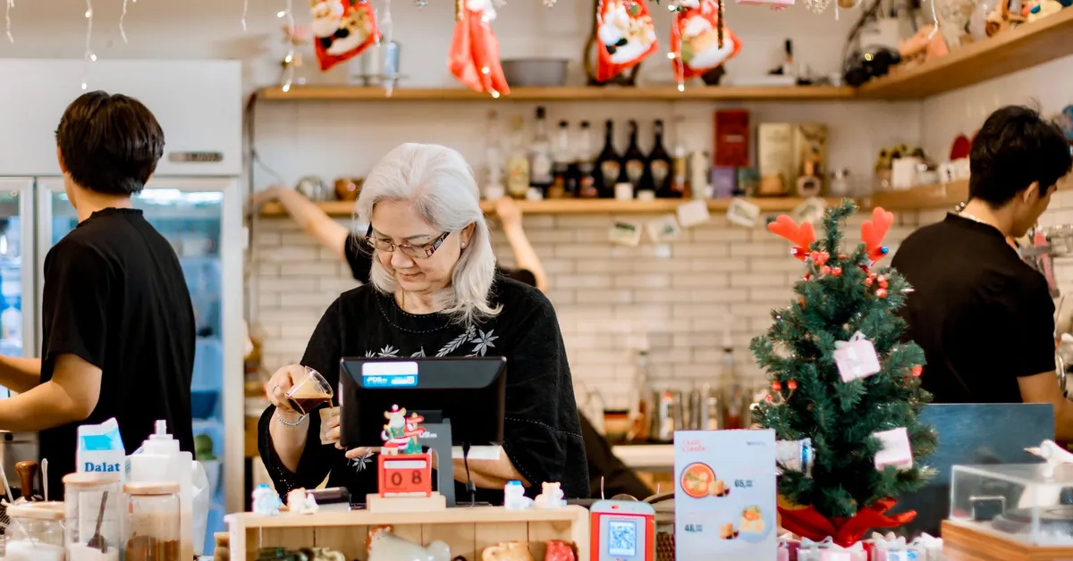 Elderly woman managing a festive cafe counter during Christmas season. festive cafe scene with elderly woman at counter