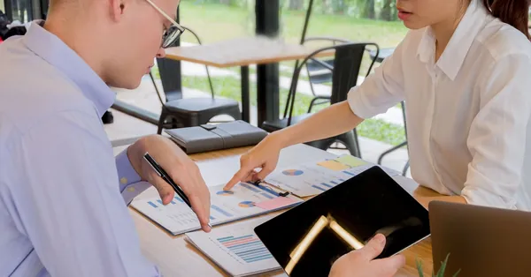 Team collaboration over financial documents in a modern office setting. woman and man sitting facing table