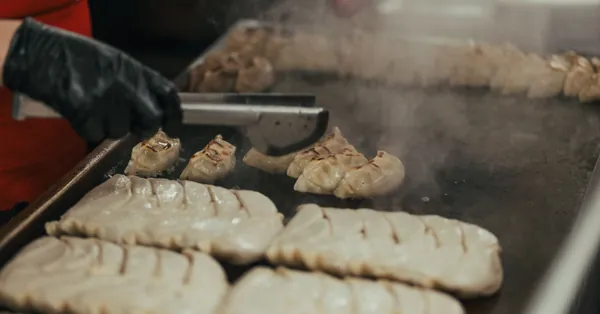 Close-up of a chef cooking dumplings on a griddle in a commercial kitchen. man frying meat in kitchen