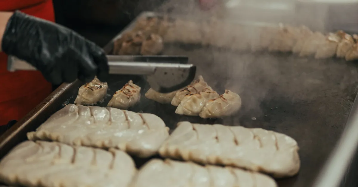 Close-up of a chef cooking dumplings on a griddle in a commercial kitchen. man frying meat in kitchen