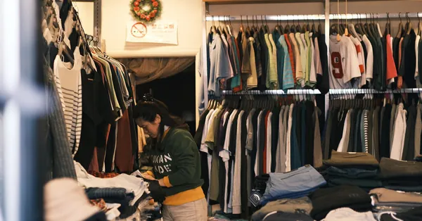 A woman organizing clothes in a cozy boutique clothing store with a wide selection on display. woman working at clothes store