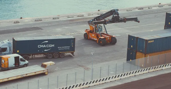 View of a busy container terminal with trucks and forklifts managing cargo under daylight. container terminal operations with forklift and trucks