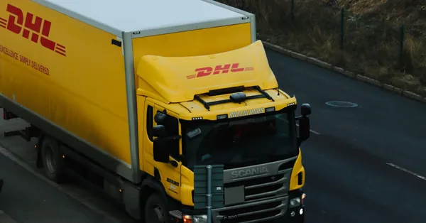 Yellow DHL delivery truck driving along a city road showcasing logistics in action. big dhl truck