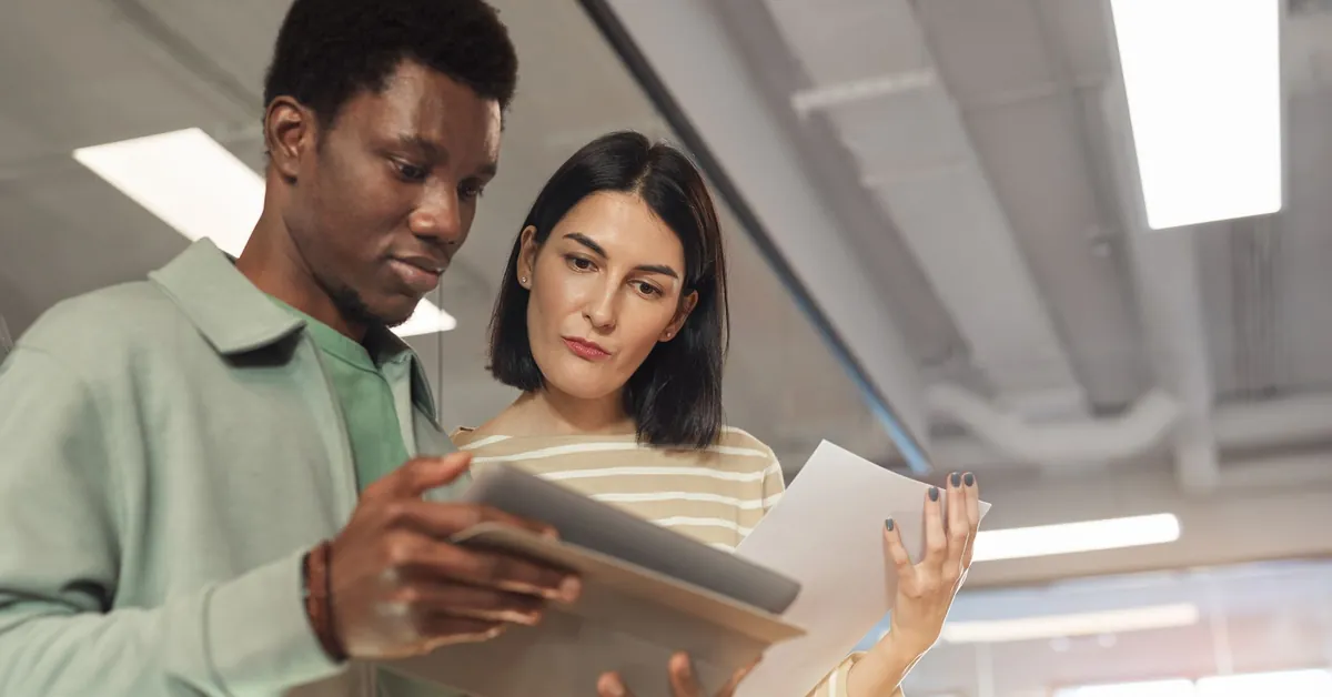 Two professionals collaborating on a project using a digital tablet in a modern office setting. man and woman looking at a digital tablet