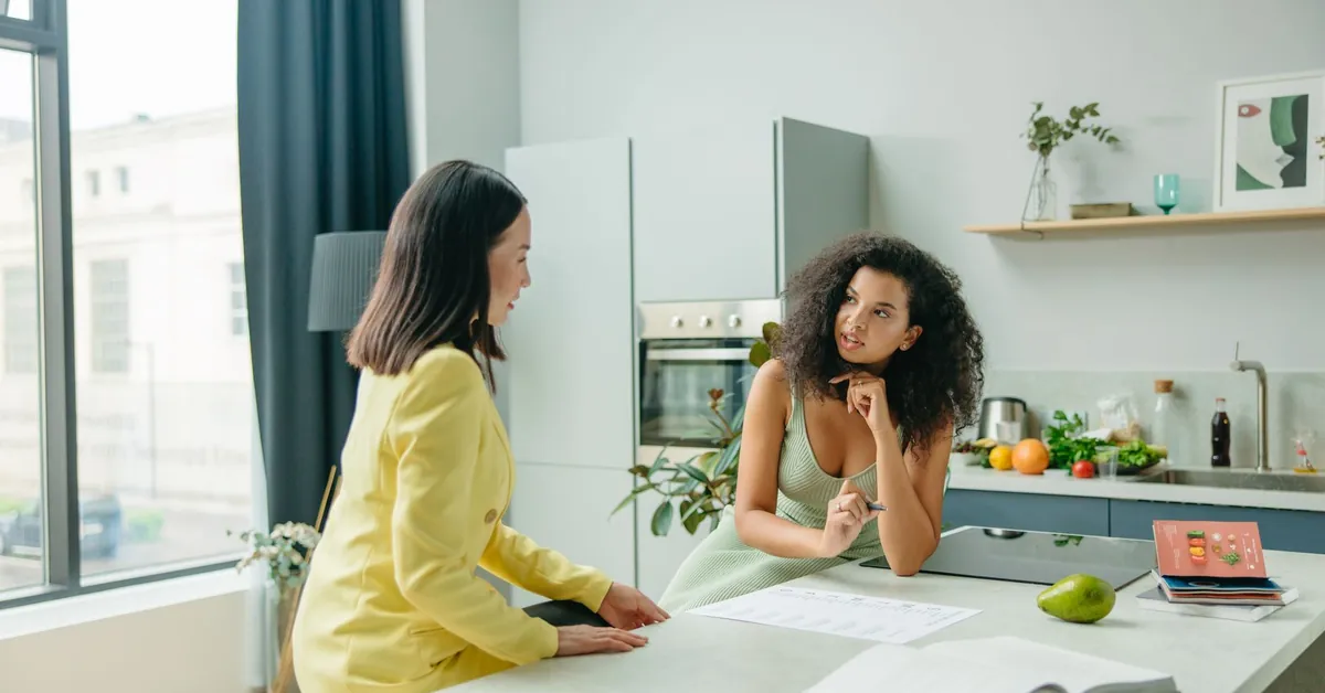 Two women engage in a conversation about nutrition in a stylish kitchen setting. food man love people
