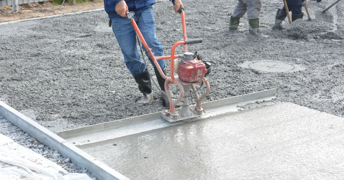 Team of construction workers using power tools to level freshly poured concrete on a building site. construction workers smoothing fresh concrete outdoors