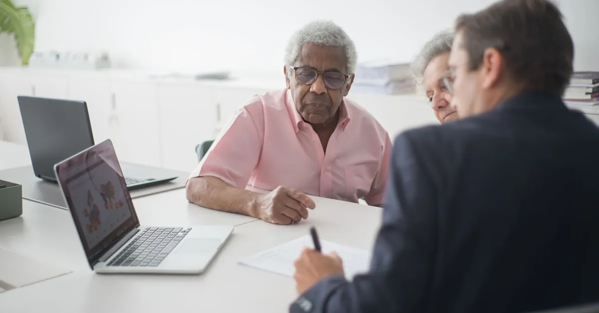 Senior couple discussing insurance options with a consultant in an office setting. elderly couple discussing contract with consultant