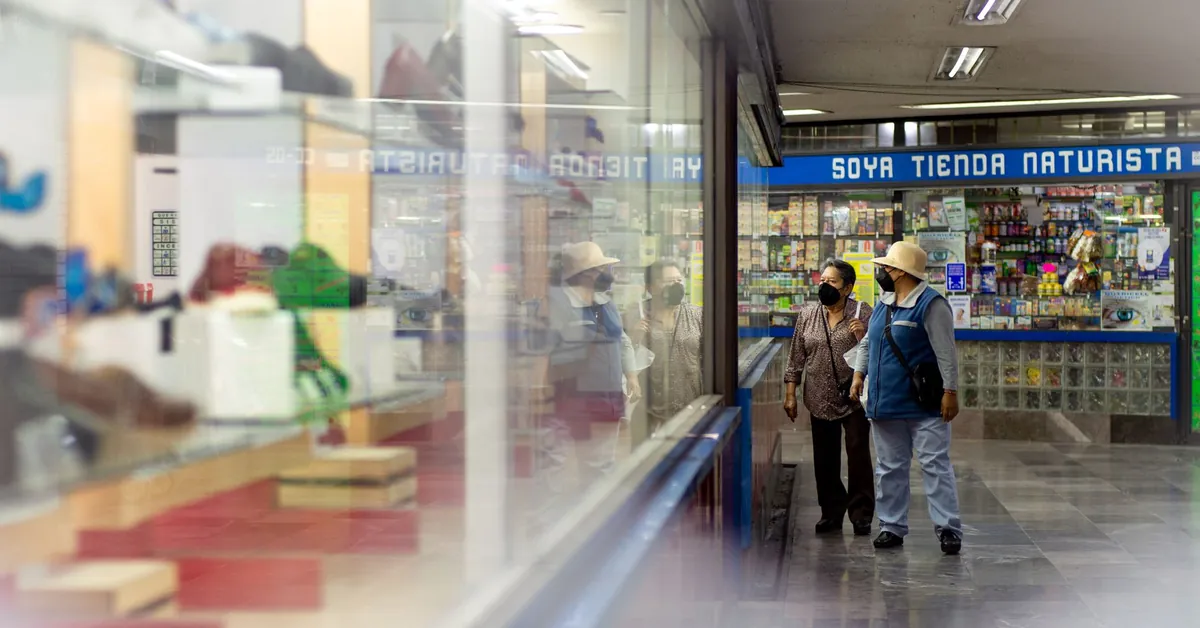 Adults wearing masks shop indoors at a marketplace, reflective display in view. elderly couple inside a mall